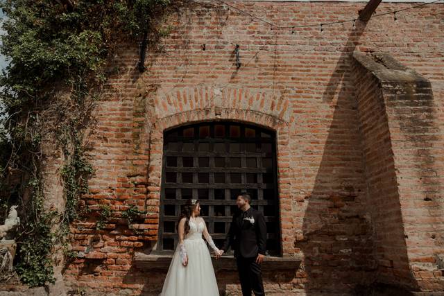 Novios agarrados de la mano frente a una ventada antigua
