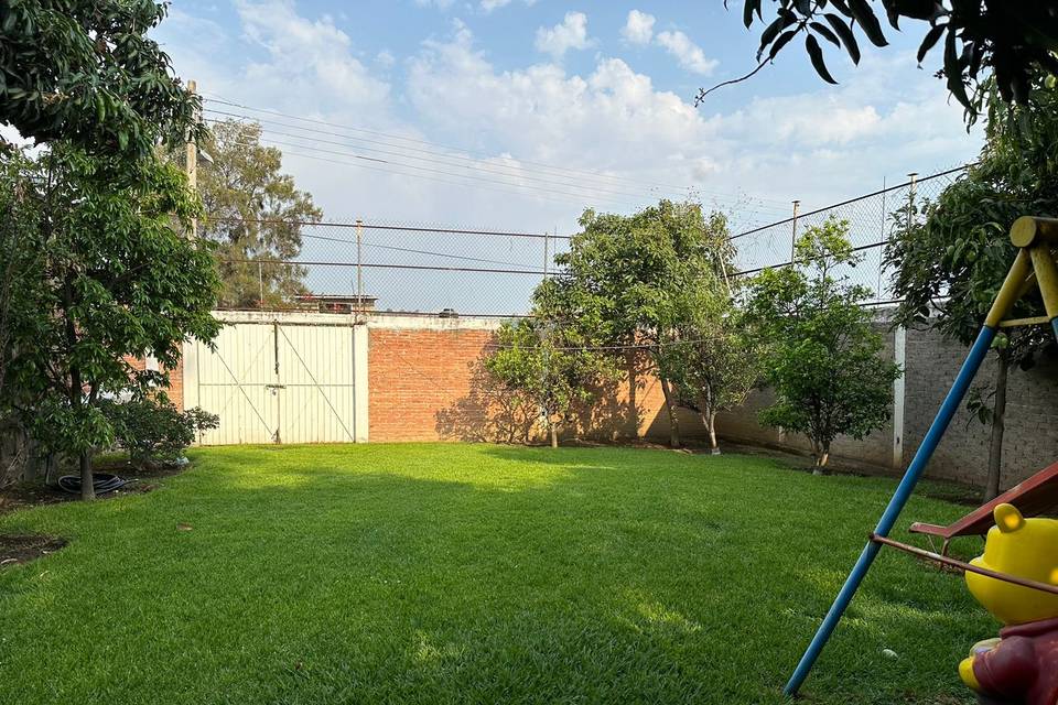 Jardín con puerta blanca y árboles