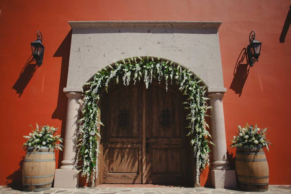 Entrada con puerta de madera y arco de flores