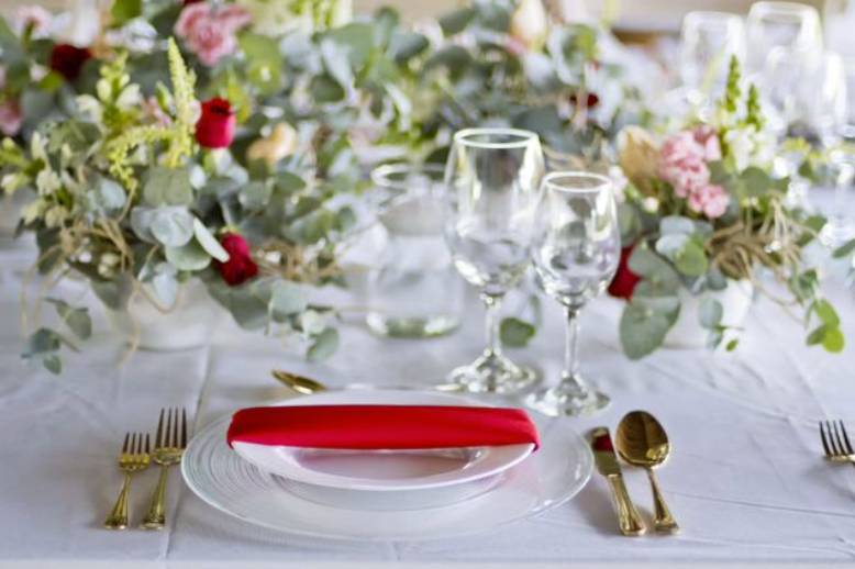 Mesa con cubiertos dorados y servilleta roja