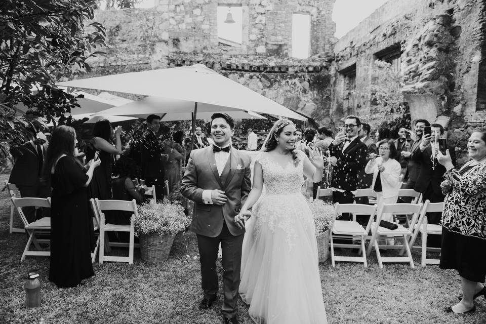 Pareja sonriendo y caminando entre sus invitados