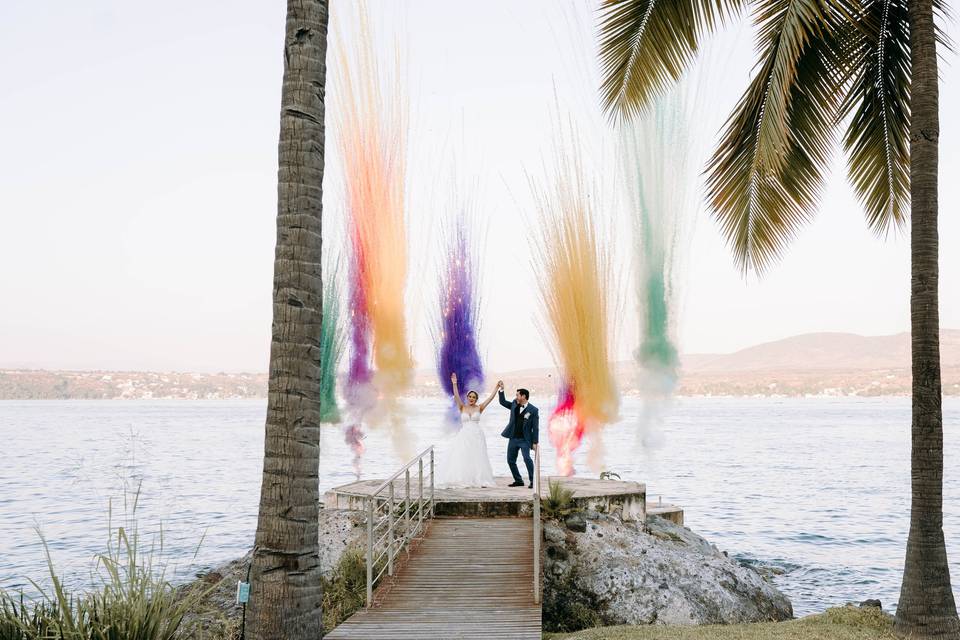 Novios frente a un lago con humo de colores