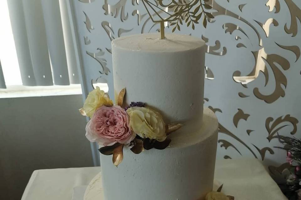 Pastel blanco con líneas doradas y flores rosas y blancas