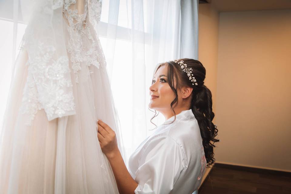 Novia mirando su vestido colgado en la ventana