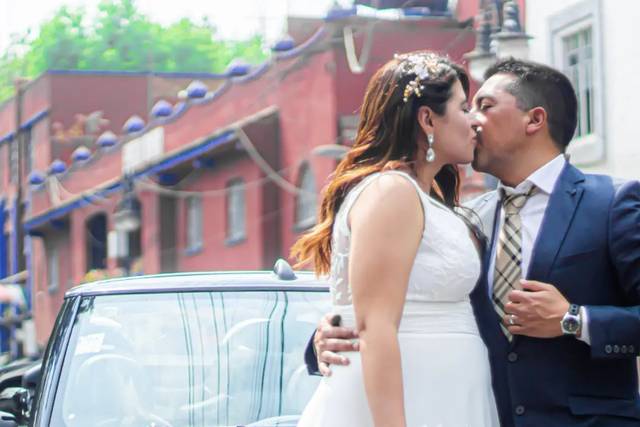 Novios dándose un beso frente a un auto blanco