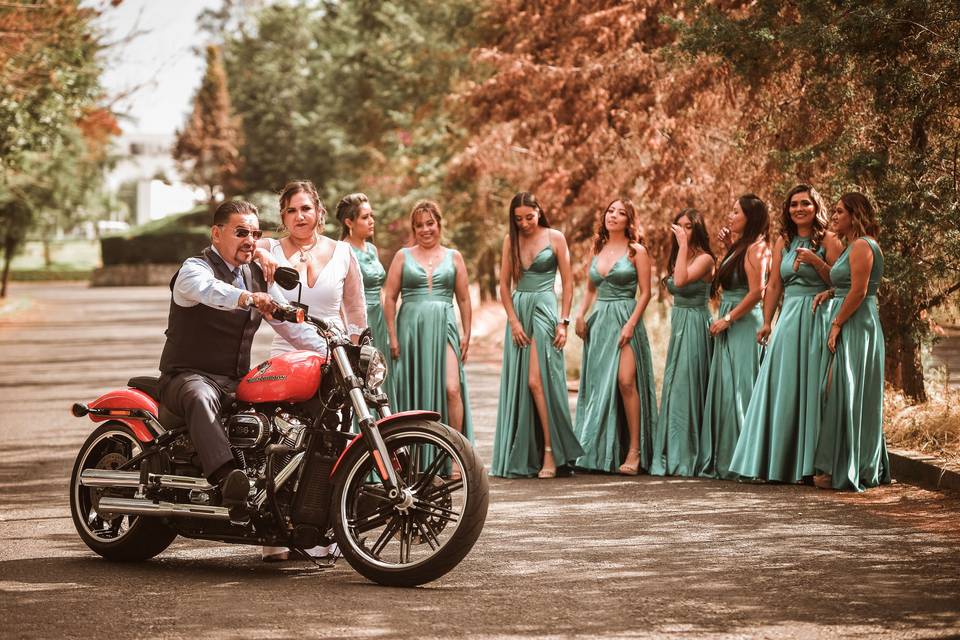 Novio en una moto y novia esperándolo junto a sus damas de honor