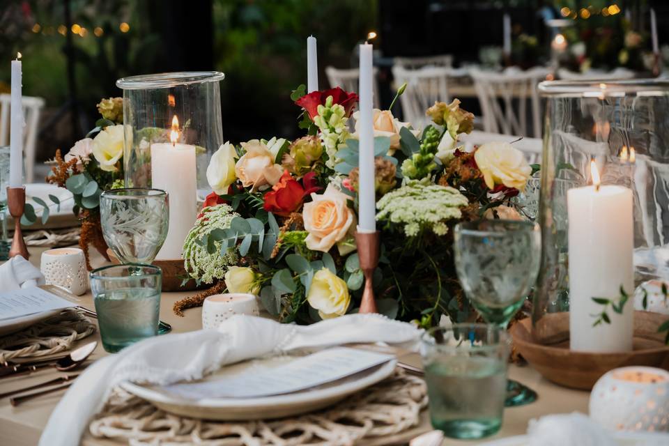 Mesa con copas verdes, velas, arreglo floral