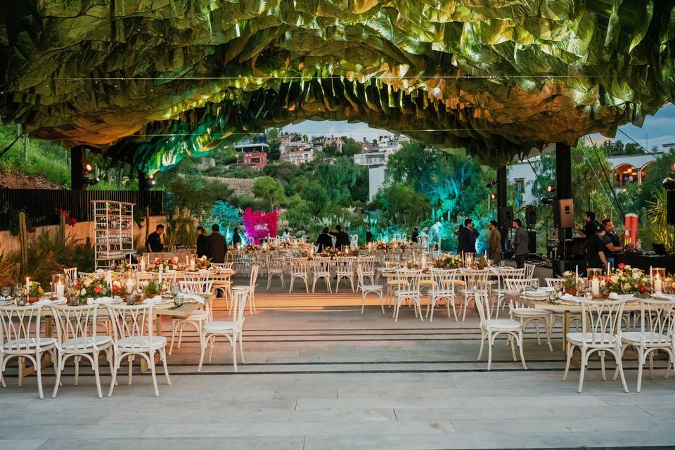 Montaje de mesas en el salón con un techo de follaje