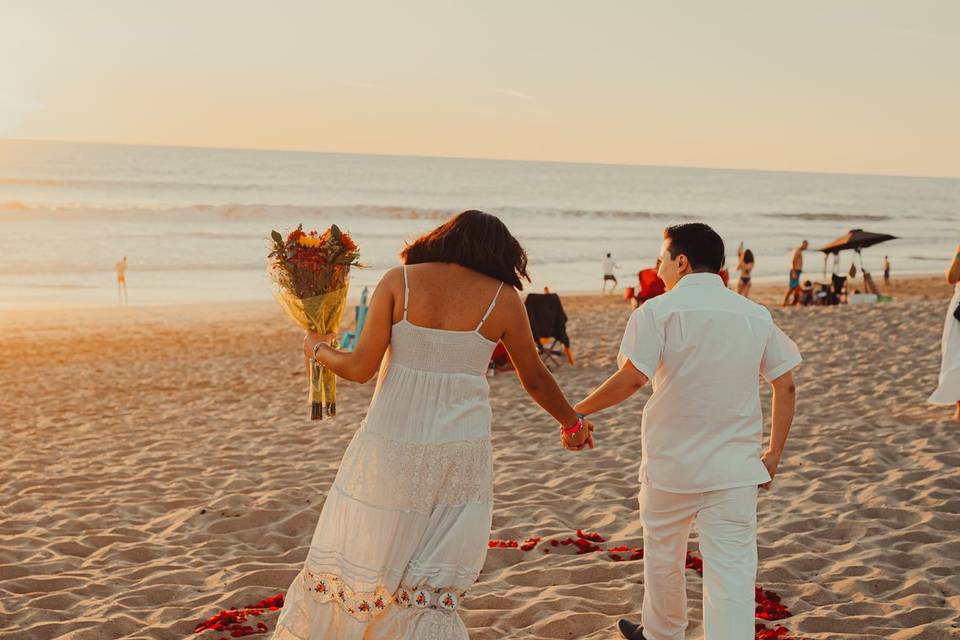 Novios agarrados de la mano caminando por la playa