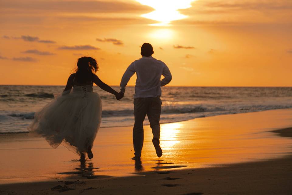 Pareja corriendo por la playa en el atardecer