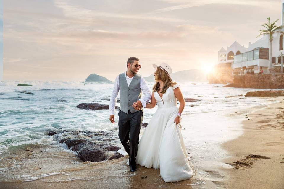 Pareja agarrada de la mano caminando por la playa