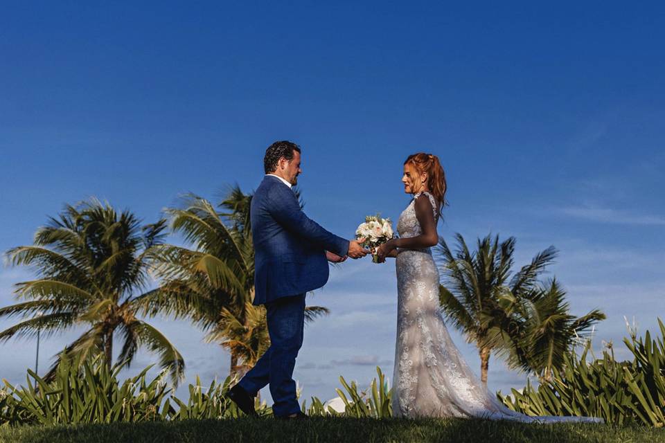 Novios agarrados de la mano frente a las palmeras