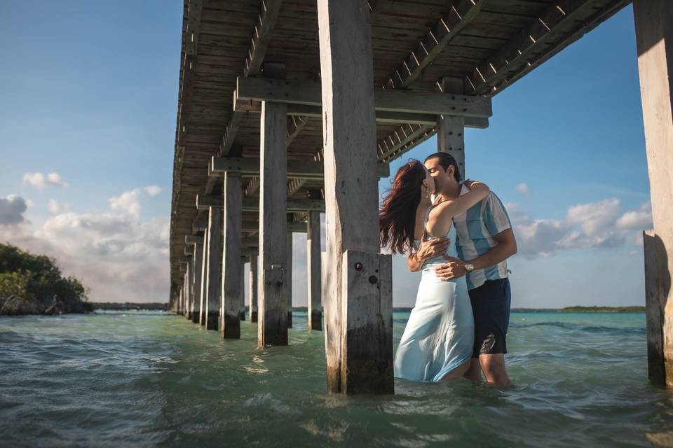 Pareja besándose debajo de un puente de madera