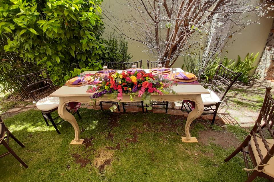 Mesa de novios en un jardín decorada con flores de colores