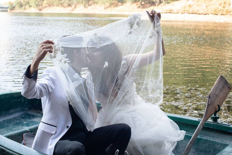 Novios en un bote dándose un beso detrás del velo de novia