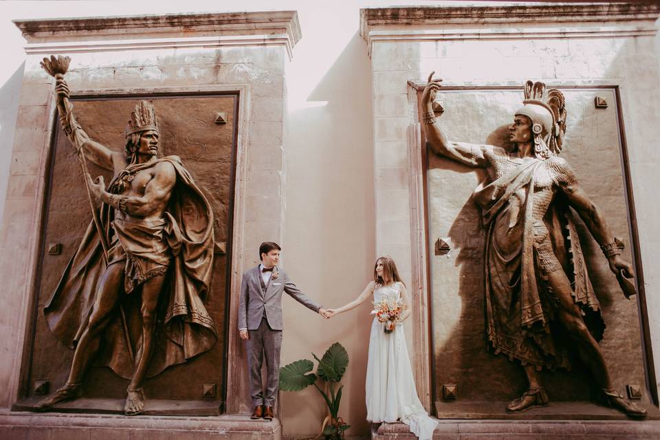 Pareja agarrada de la mano frente a dos estatuas