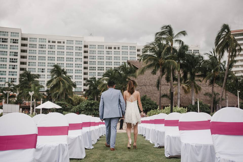 Novios de espaldas caminando entre las sillas