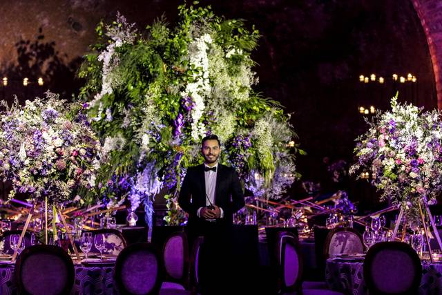 Novio posando en medio de adornos de flores