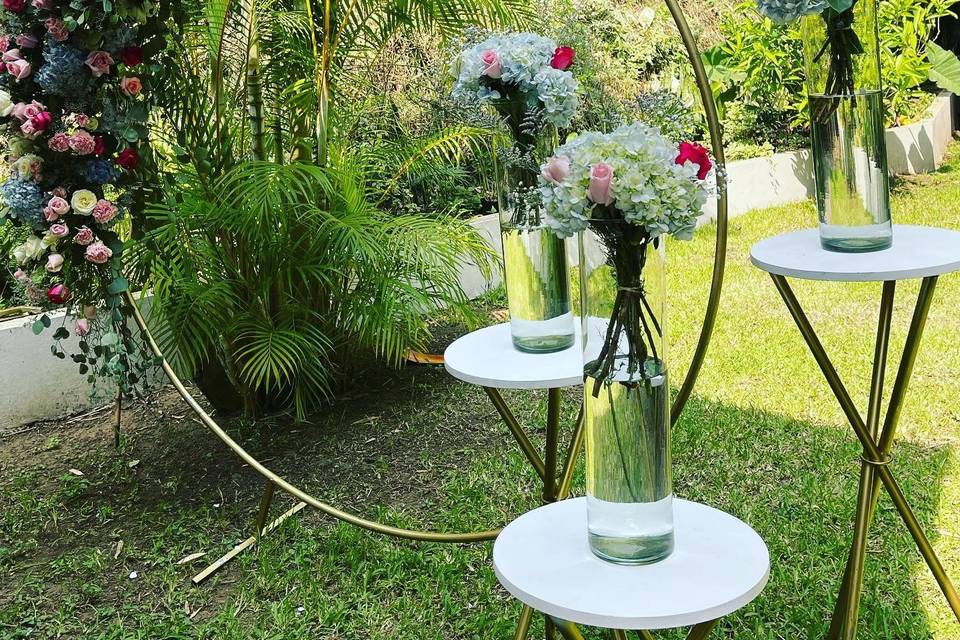 Arco de rosas con arreglos florales en vasos transparentes