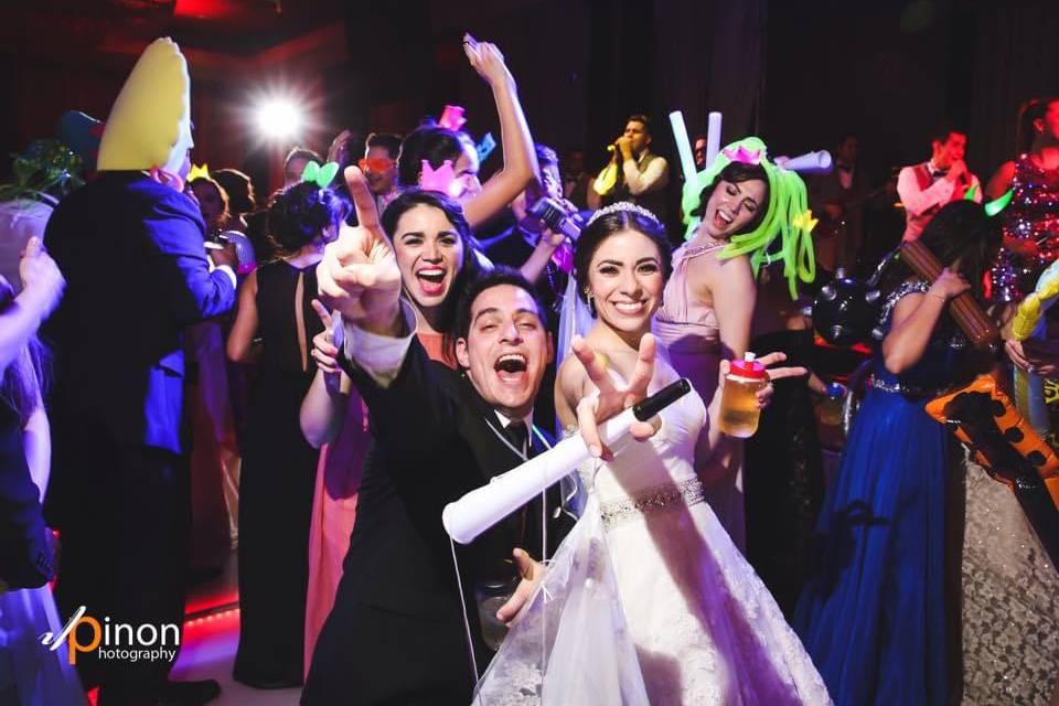 Novios felices e invitados detrás de ellos bailando