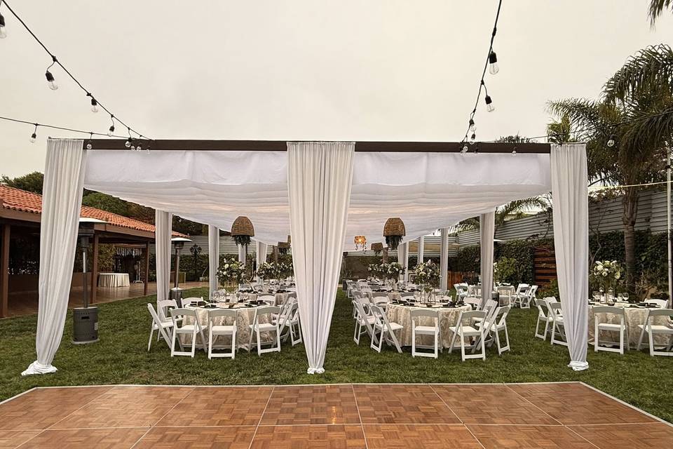 Pista de baile de madera y carpa blanca con sillas y mesas