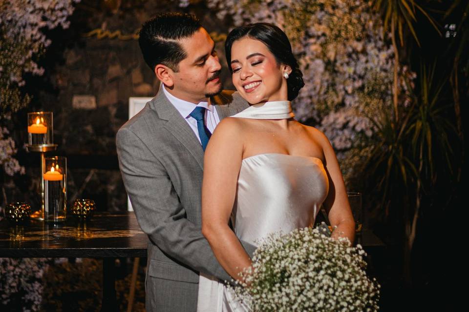 Recién casados posando frente a un arco de flores