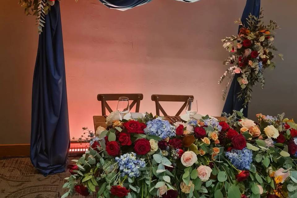 Mesa de novios con flores rojas, azules y blancas