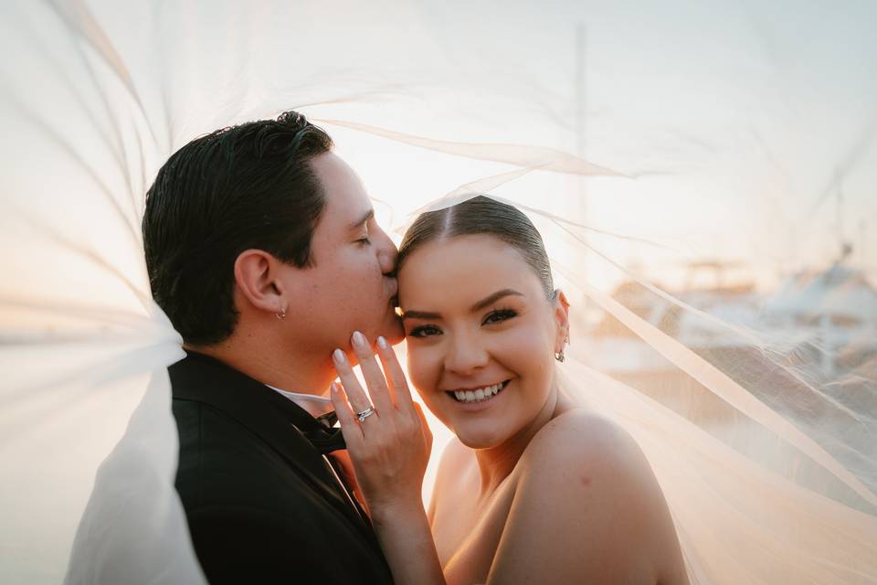 Novio dándole un beso a la novia bajo el velo