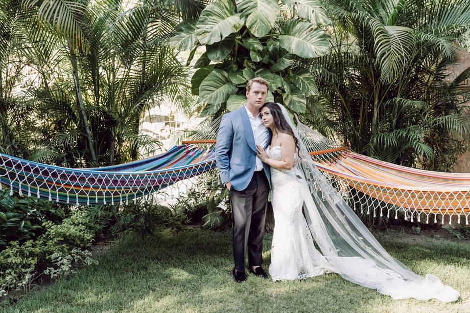 Novios posando en el jardín frente a unas hamacas