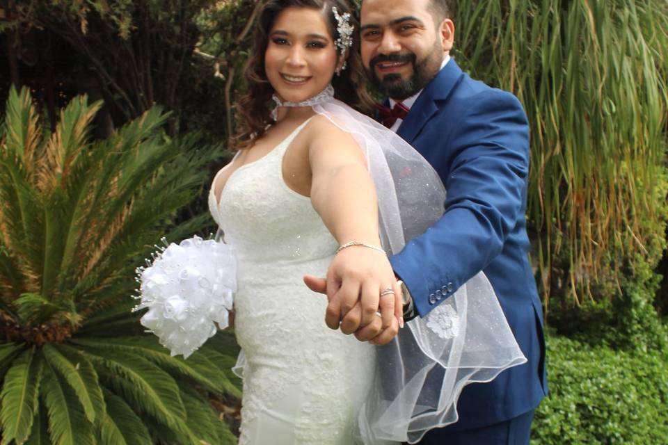 Novios agarrados de la mano en un jardín