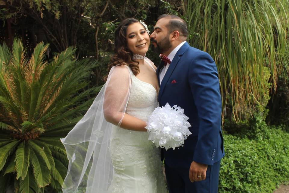 Novio dándole un beso a la novia en el jardín