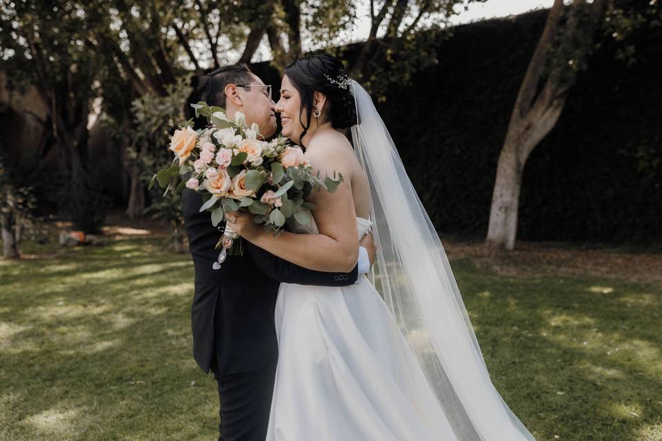 Novios sonriendo y abrazados en el jardín