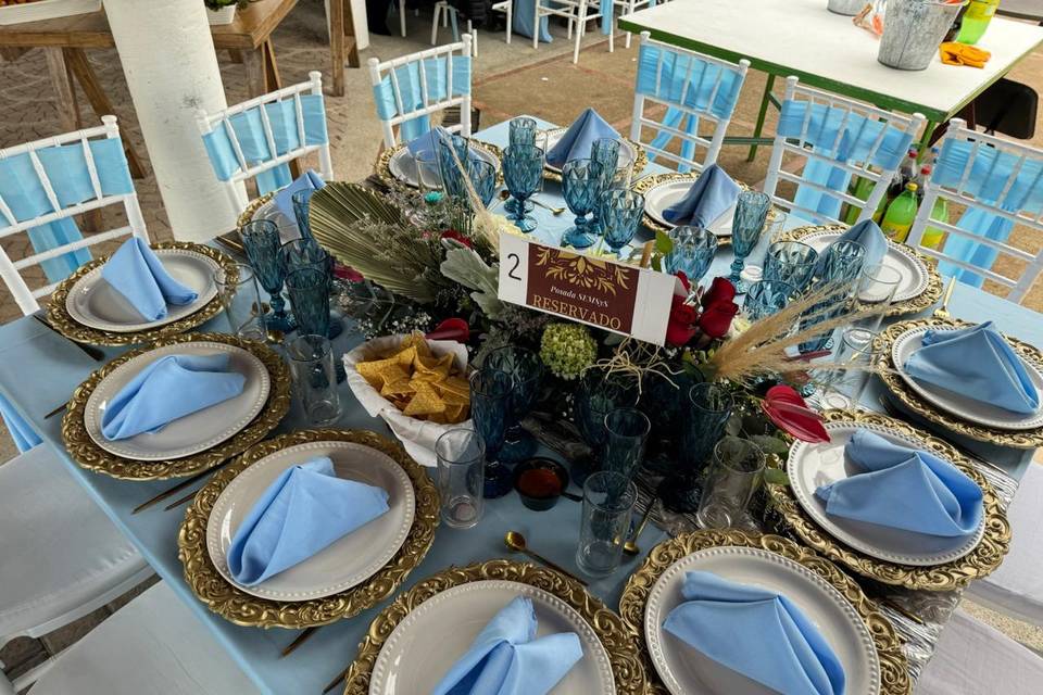 Mesa con mantel azul y platos blancos y dorados