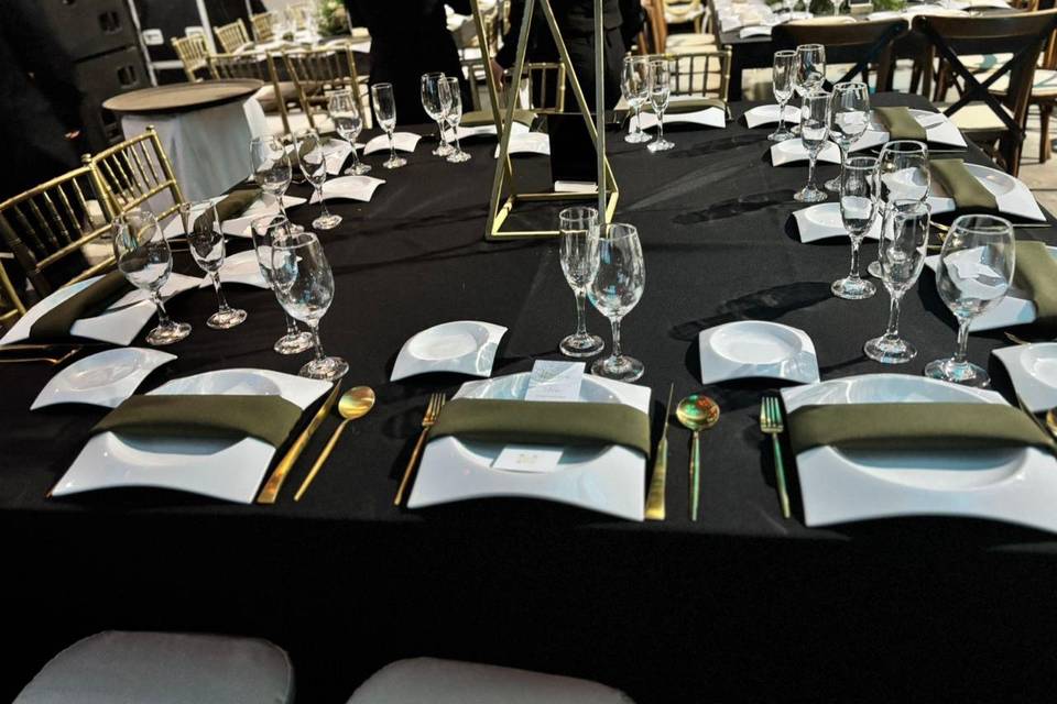 Mesa con mantel negro y cubiertos dorados