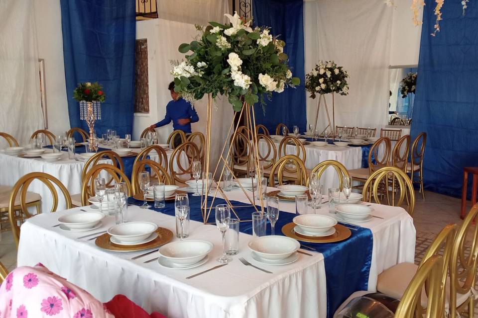 Mesas cuadradas con mantel blanco y azul rey con arreglos florales blancos