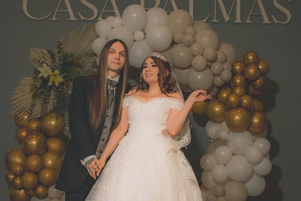 Novios posando frente a un arco de globos