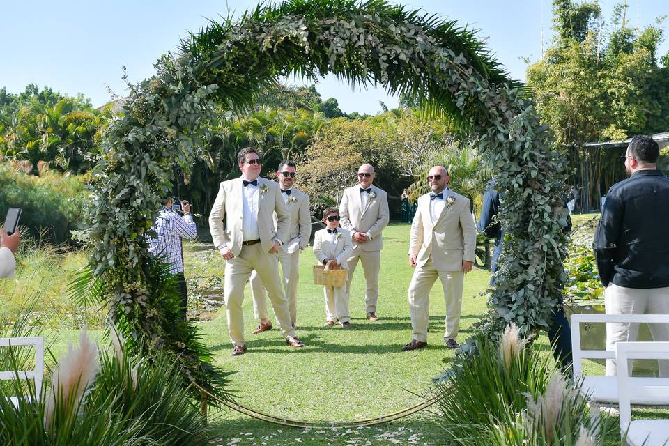 Bestmen en el jardín detrás de un arco de flores