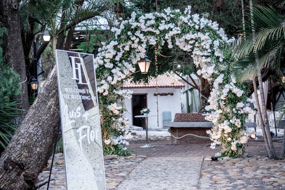 Entrada decorada con un arco de flores blancas