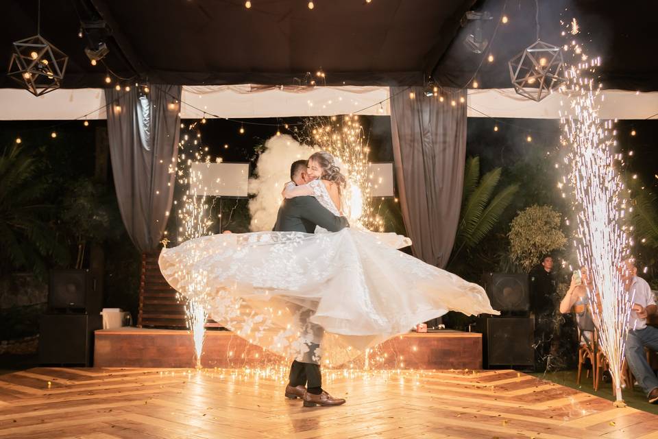 Novio cargando a la novia en la pista de baile con chisperos