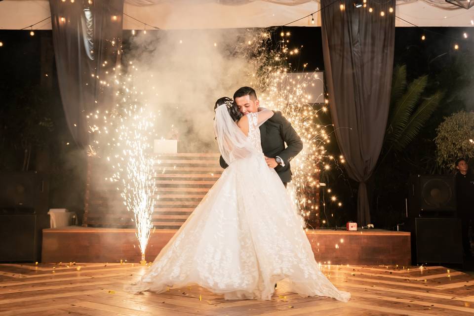 Novios bailando con chisperos de fondo