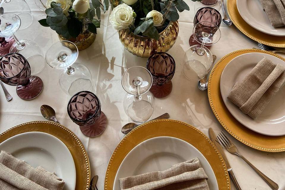 Centros de mesa con copas vino y platos dorados