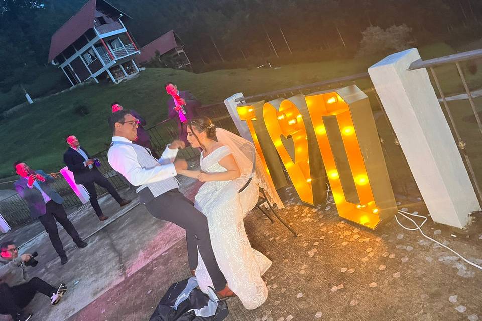 Novios bailando frente a letras gigantes led