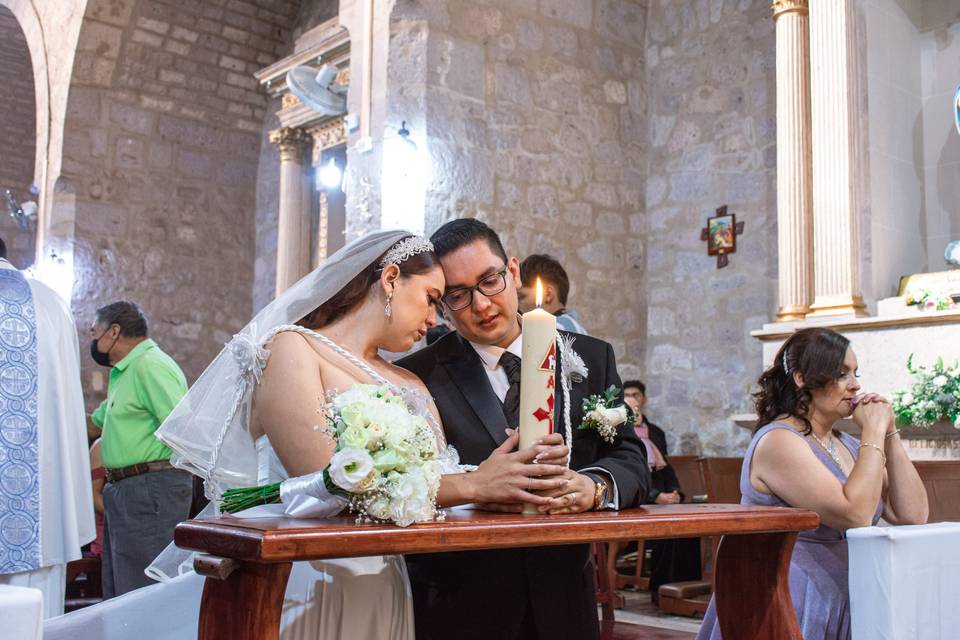 Novios en la iglesia sosteniendo un cirio