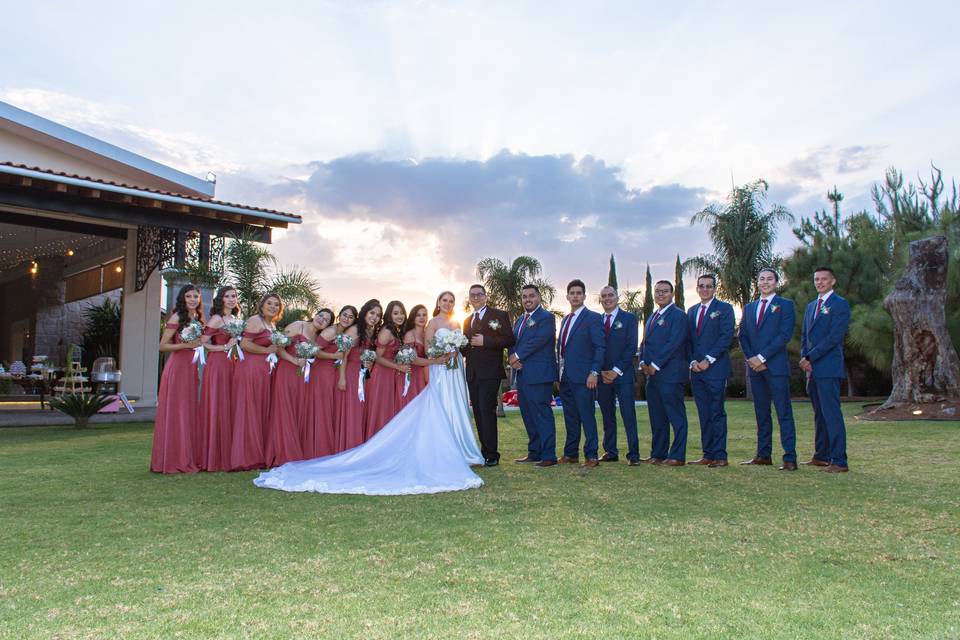 Novios posando con sus damas de honor y sus bestmen en el jardín