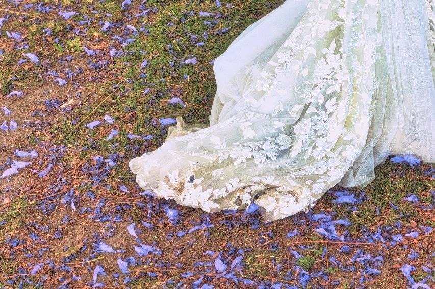 Cola del vestido de novia en el jardín con pétalos morados
