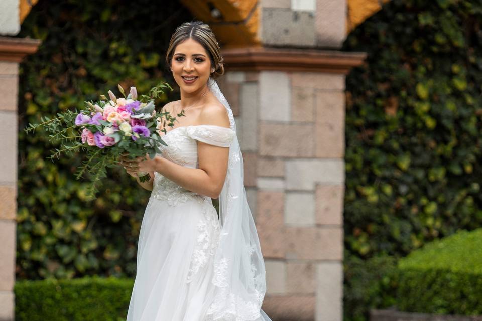 Novia posando en el jardín sosteniendo su ramo