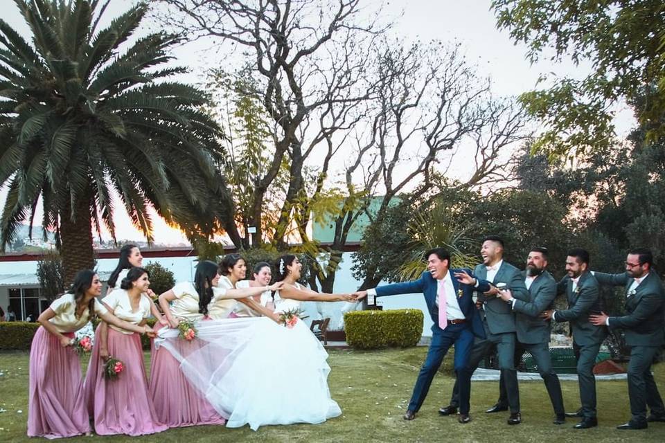Novios posando en el jardín con sus damas de honor y padrinos