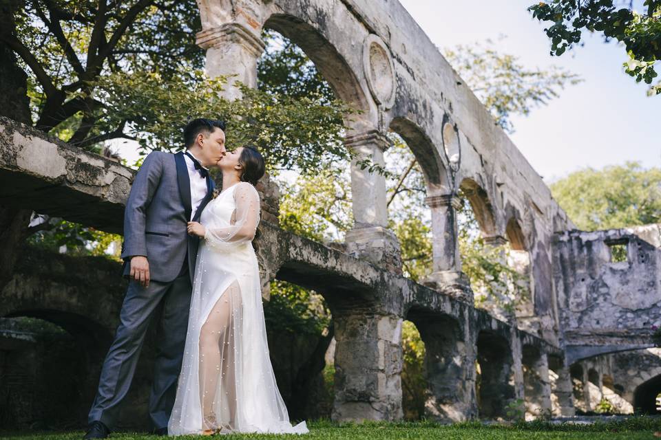 Novios besándose frente a unos arcos