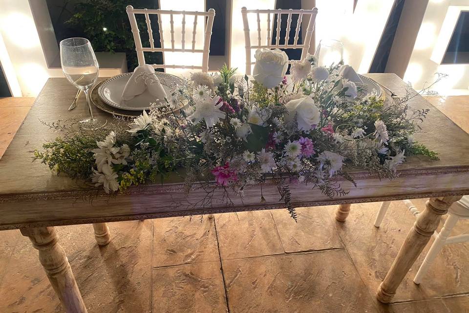 Mesa de novios de madera con arrgeglo flroal de rosas blancas