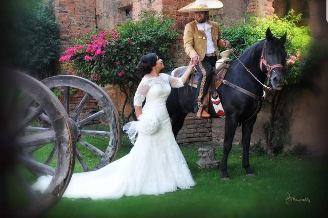 Novio sobre un caballo vestido de charro sosteniendo la mano de la novia